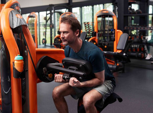 Older man doing crunch exercise on a fitness machine in the Basic-Fit gym