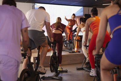 A woman is riding an orange indoor bike on a stage with red lighting.