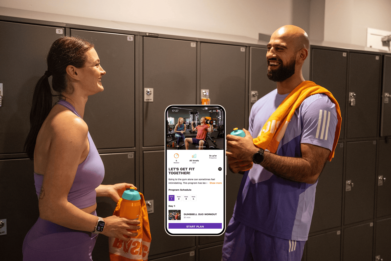 Two people in gym locker room smiling and holding water bottles, with a smartphone screen in the center displaying a workout app called “Let’s Get Fit Together!” showing a dumbbell duo workout program.