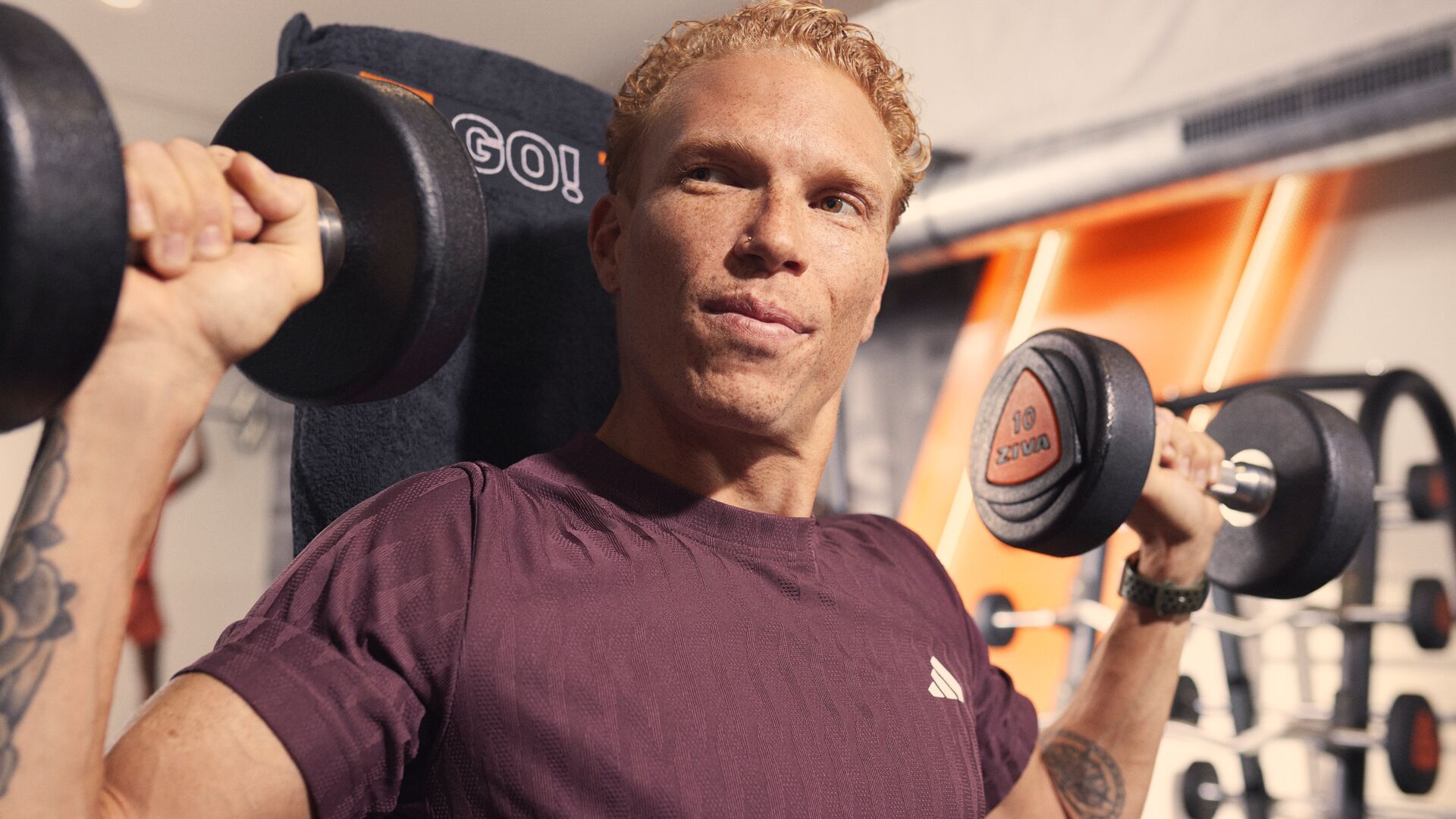 Mann macht Schulterdrücken mit Kurzhanteln im Fitnessstudio