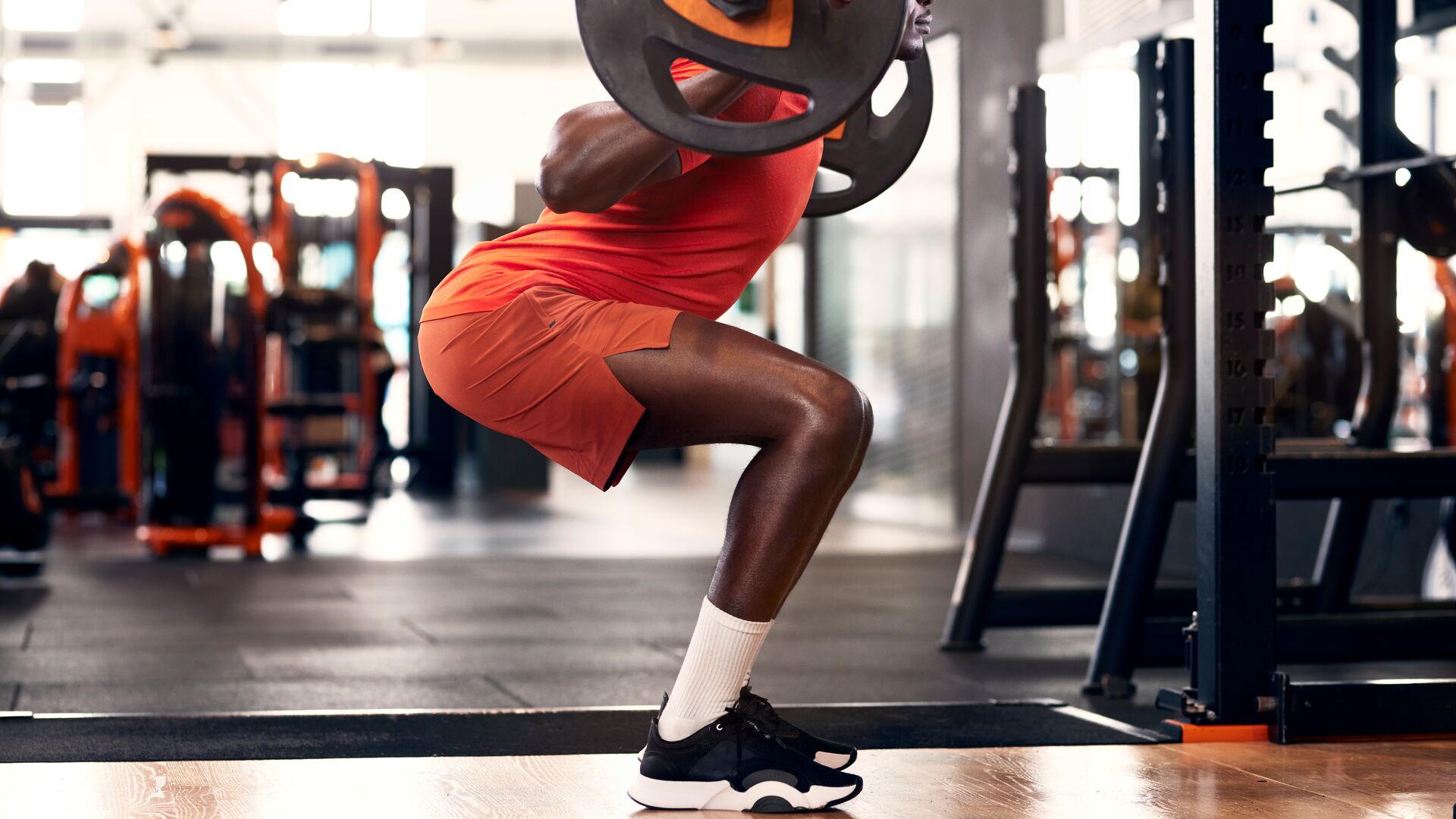 Man performing barbell squats at the gym to build stronger glutes
