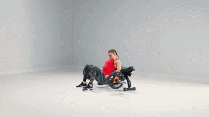 Frau in der Startposition für einen Hip Thrust auf einer Bank, mit flachen Füßen am Boden und Schultern aufgestützt