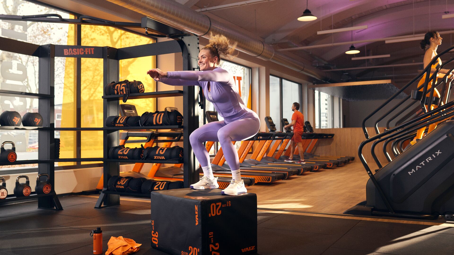 Femme effectuant un box jump dans l’espace d’entraînement fonctionnel d’un club Basic-Fit