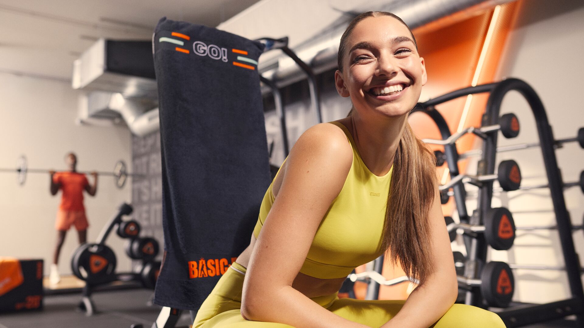 Frau lächelt, während sie auf einem Kraftgerät im Fitnessstudio pausiert