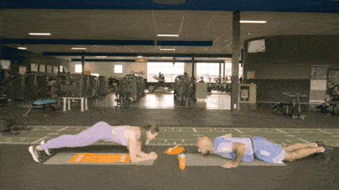 One person performing burpees while the other holds a plank position next to them, then switching roles to alternate work and rest.