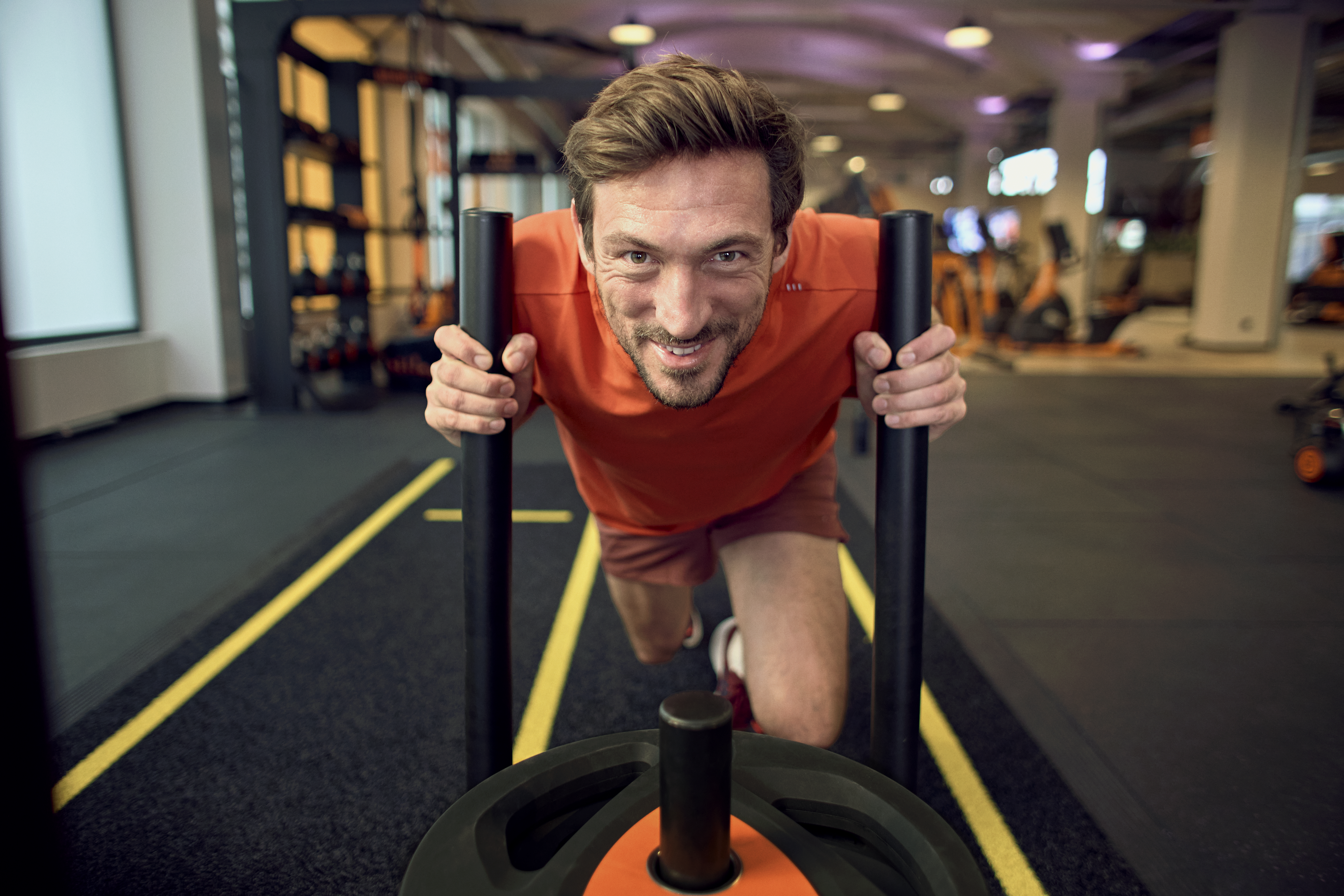 Man pushing a sled during an intense gym workout.